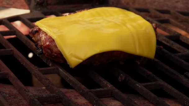 Een vlees cutlet voor een hamburger met cheddar kaas op de top is braden op de grill — Stockvideo