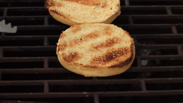 Kitchen tongs are taking grilled bun for burgers from the grill — Stock Video