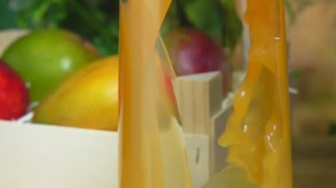 Taze mango suyu, mango dolu ahşap kutunun yanındaki sürahiye dökülür.