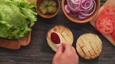 Ev yapımı ızgara burgerin üzerine yayılan domates sosunun en üst görüntüsü.