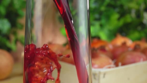 Close-up van granaatappelsap gegoten in een kruik naast een doos vol granaatappels — Stockvideo