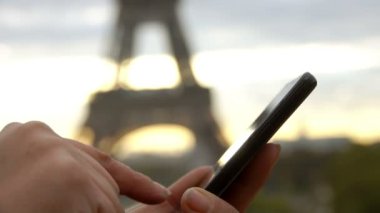 Kadın eli gün doğumunda telefon ekranına tıklıyor.