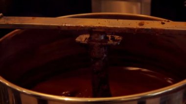 Büyük şekerleme karıştırıcısı erimiş siyah çikolatayı karıştırıyor. 