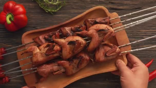 Close-up top view of hands placing a plate full of grilled quails on the table — Stock Video