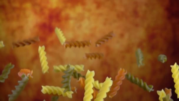 Macarrão colorido fusili está voando sobre um fundo ocre amarelo — Vídeo de Stock