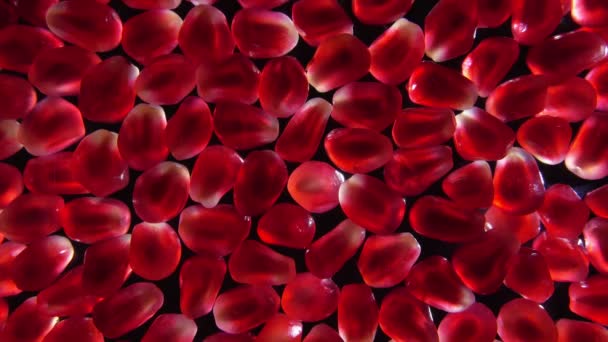 Sweet red juice is flowing on the red pomegranate grains on the dark background — Stock Video