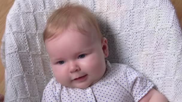 Un petit adorable bébé aux yeux bleus sur une couverture en tricot blanc — Video