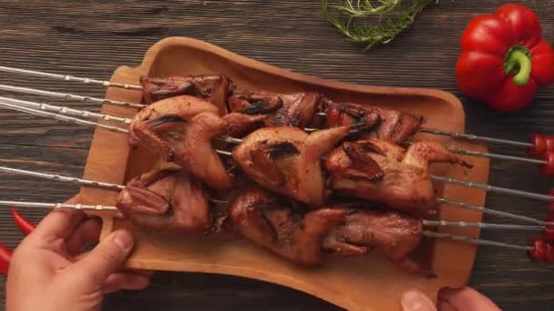 Male hands placing a plate full of grilled quails on the skewers on the table — Stock Video