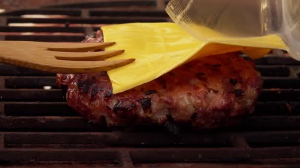 Close-up do queijo cheddar colocado na costeleta de hambúrguer caseiro na grelha — Vídeo de Stock