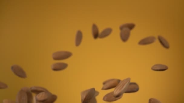 Κοντινό πλάνο από νόστιμα αμύγδαλα που πετούν και περιστρέφονται στο κίτρινο φόντο — Αρχείο Βίντεο