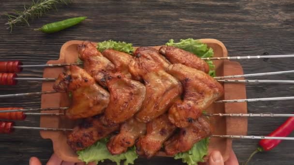 Masaya yerleştirilmiş şişler üzerinde kızarmış tavuk kanatlarıyla dolu tabağın üst görüntüsü. — Stok video
