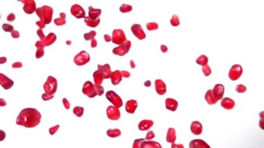 Beyaz arka planda olgun nar taneleri zıplıyor.