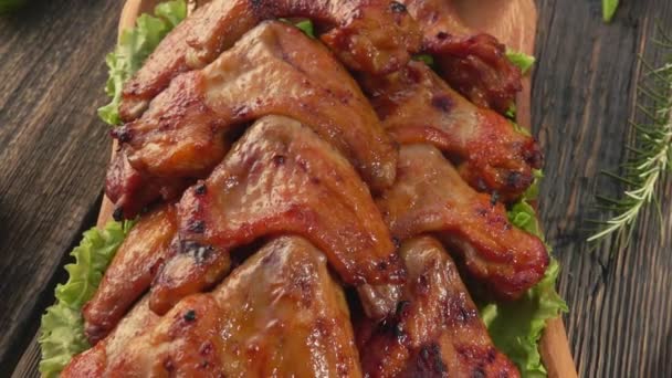 Panorama in alto delle ali di pollo fritto sugli spiedini sul piatto di legno — Video Stock