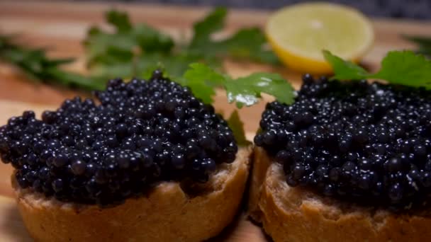 Close-up of delicious black caviar spread on the slice of bread — Stock Video