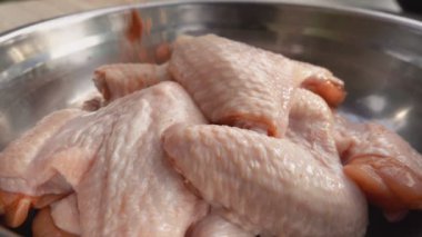 Baharat ve tuz karışımı kasedeki çiğ tavuk kanatlarına dökülüyor.