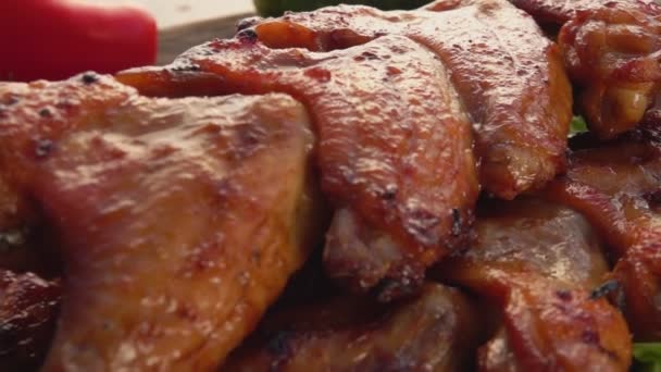 Panorama de asas de frango fritas nos espetos no fundo de legumes — Vídeo de Stock