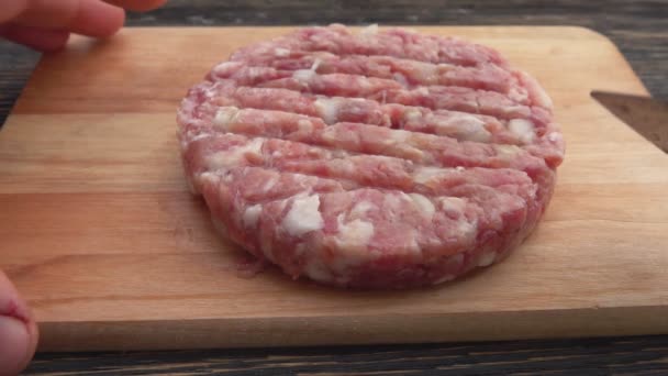 Zbliżenie kotleta z surowego mięsa z cebulą z deski drewnianej — Wideo stockowe
