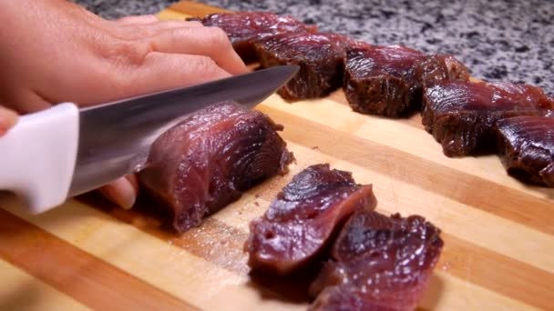Las manos femeninas están cortando pescado de atún crudo en trozos en una tabla de madera — Vídeos de Stock