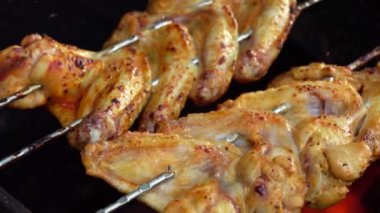 Şişe yakın çekim iştah açıcı tavuk kanatları ateşin üstünde kızarıyor.