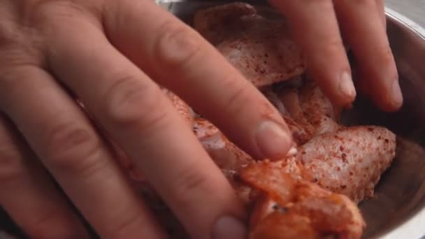 Las manos masculinas están mezclando las alas de pollo crudo con especias y sal en el tazón — Vídeos de Stock