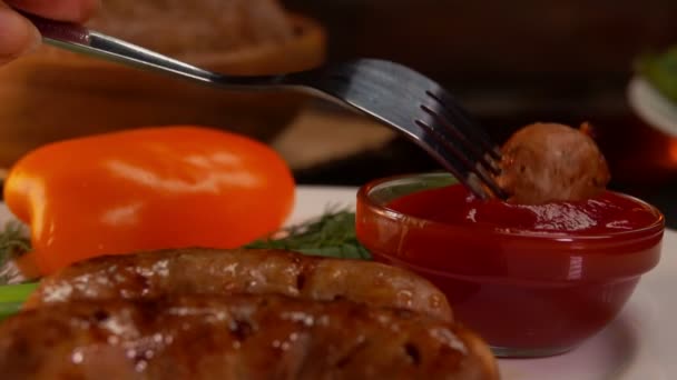 Widelec z kawałkiem smażonej kiełbasy jest zanurzony w ketchupie — Wideo stockowe