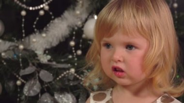 Noel ağacının altında oturan ve hediyeleri açan küçük bir kızın portresi.