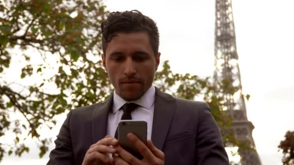 Joven hombre de negocios guapo con un traje negro lee un mensaje en un teléfono celular — Vídeo de stock