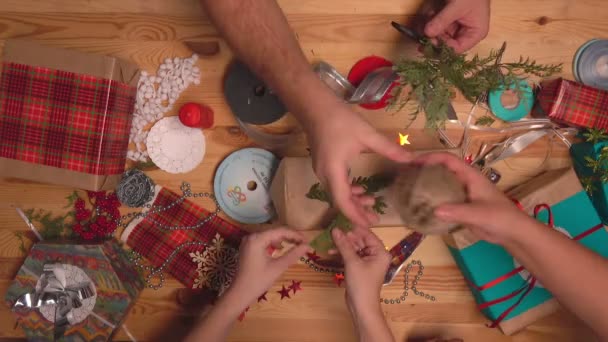 Blick von oben auf die vielen Hände, die Geschenke für Weihnachten verpacken und dekorieren — Stockvideo