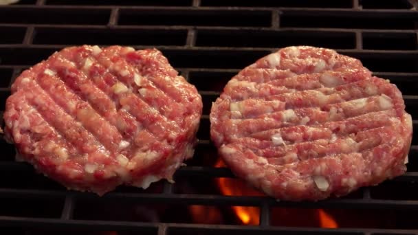 Duas costeletas de hambúrguer de carne crua com cebolas estão grelhando acima do fogo aberto — Vídeo de Stock