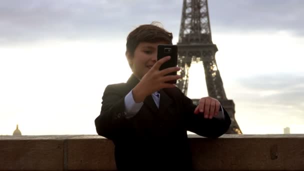 スーツの少年がエッフェル塔を背景に電話で自撮りしてる — ストック動画