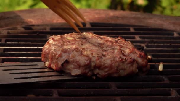 Widok z bliska pyszne kotlet burger przerzucony na grilla z łopatką — Wideo stockowe