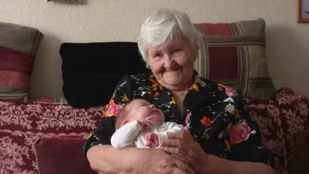 Una vecchia nonna sta cullando un bambino tra le sue braccia — Video Stock