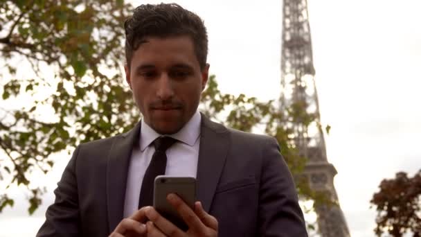 Joven empresario atractivo en un traje negro está leyendo mensajes en un teléfono celular — Vídeo de stock