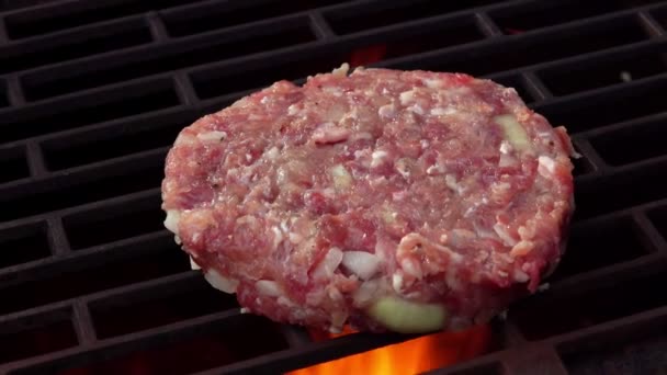 Nahaufnahme des rohen Fleisch-Burger-Schnitzels mit Zwiebeln, die über dem offenen Feuer braten — Stockvideo