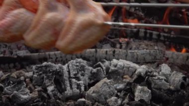 Çiğ salamura edilmiş tavuk kanatları yanan kömürlerin üzerine konur.