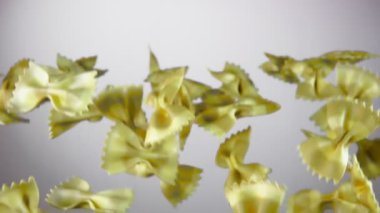 Kuru çizgili makarna Farfalle beyaz arka planda uçuyor.