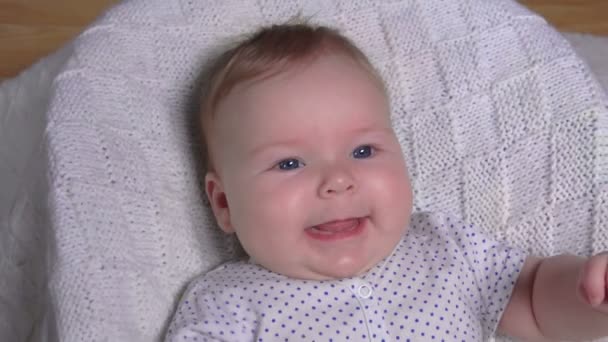 Un bébé gai mignon dans un costume blanc à pois agite ses mains — Video