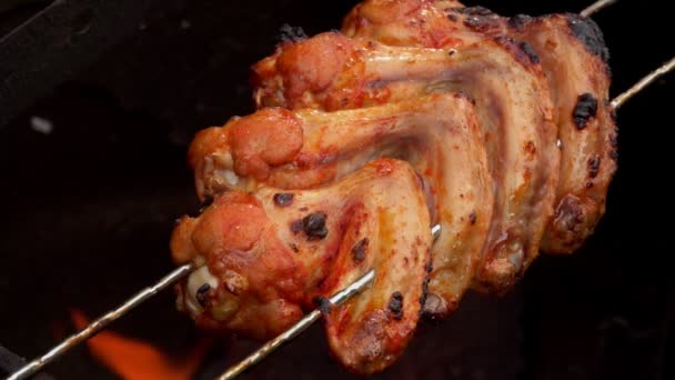 Deliciosas alitas de pollo frito están chisporroteando en la parrilla por encima de un fuego abierto — Vídeo de stock
