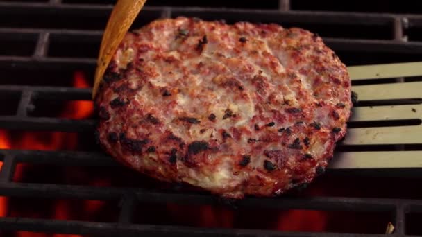 Primo piano della cotoletta di hamburger appetitosa con cipolle che si capovolgono sopra il fuoco — Video Stock