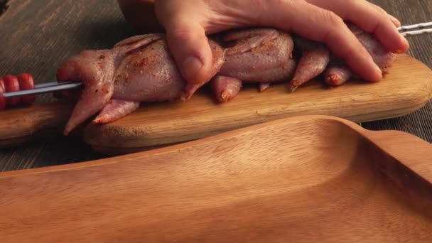 Close-up of chiefs hands putting raw marinated quails on the skewers — Stock Video