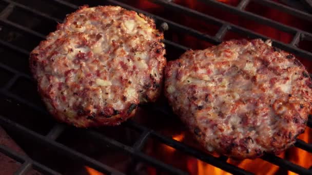 Zwei Fleischburger Schnitzel mit Zwiebeln braten auf dem Grill über dem offenen Feuer. — Stockvideo