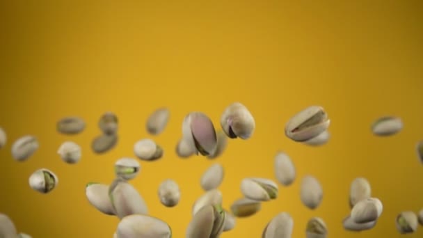 Крупный план соленых фисташек, летящих на желтом фоне — стоковое видео