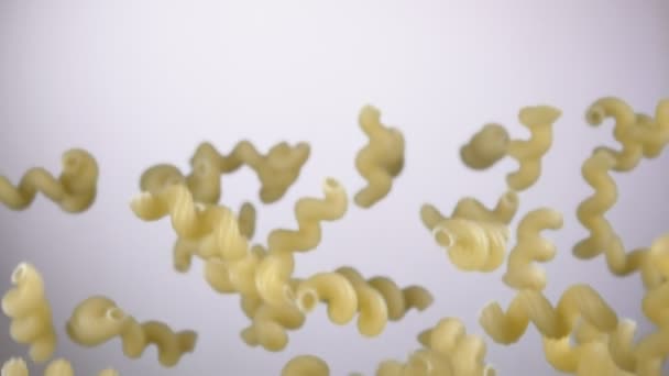 Droge pasta cellentani vliegt omhoog op een witte achtergrond — Stockvideo