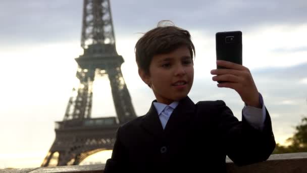 En leende tonåring i svart kostym tar en selfie vid soluppgången. — Stockvideo