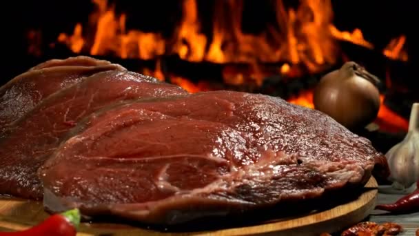 Bifes de carne crua deliciosos estão deitados na tábua de madeira ao lado da cebola — Vídeo de Stock