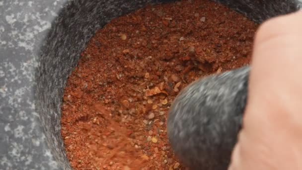 Una mano maschile macina un mix di spezie, peperoni e sale marino con un pestello. — Video Stock