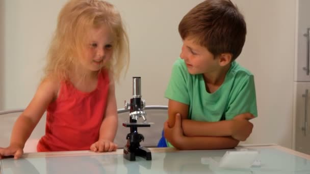 Kleine jongen en meisje zijn nieuwsgierig naar de microscoop lens — Stockvideo