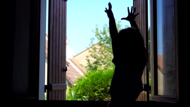 Silhueta de uma menina acenando com as mãos no fundo de uma janela aberta — Vídeo de Stock
