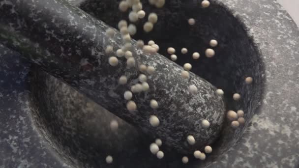 Picante exótico granos de pimienta blanca están cayendo en el mortero de piedra gris — Vídeos de Stock