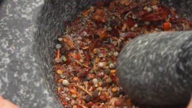 Pestle baharat, biber ve deniz tuzu öğütüp karıştırıyor.